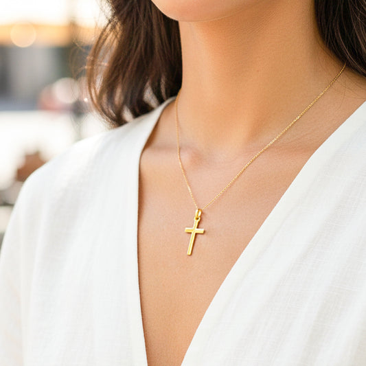 Cuello de modelo usando una cadena con un dije en forma de cruz tubo en oro amarillo de 18 quilates de Joyería Caracas.