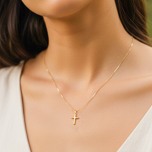 Cuello de modelo usando una cadena con un dije en forma de cruz tubo lisa en oro amarillo de 18 quilates de Joyería Caracas.