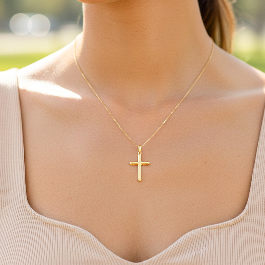 Cuello de modelo usando una cadena con un dije en forma de Cruz tubo lisa en oro amarillo de 18 quilates de Joyería Caracas.
