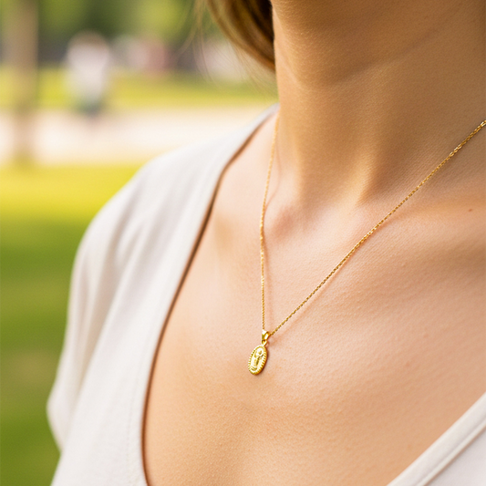 Cuello de modelo usando una cadena con un dije del Divino Niño lazo en oro amarillo de 18 quilates de Joyería Caracas.