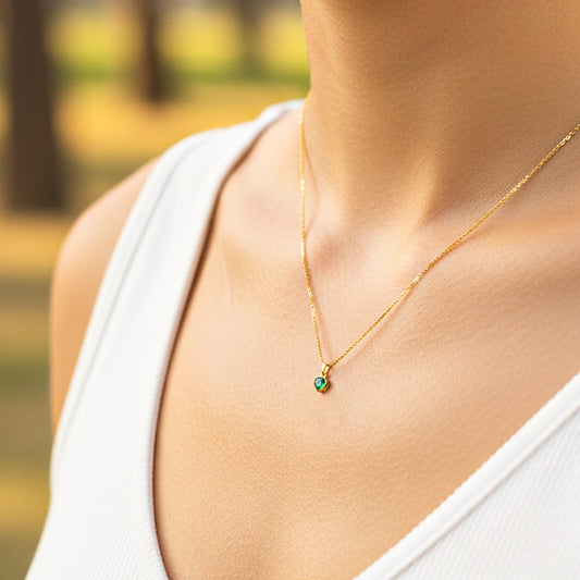 Cuello de modelo usando una cadena con un dije en oro amarillo de 18 quilates con Esmeralda en forma de corazón de Joyería Caracas.