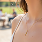 Cuello de modelo usando una cadena con un dije en forma de palabra fe en oro amarillo de 18 quilates con cristales de Joyería Caracas.
