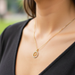 Cuello de modelo usando una cadena con un dije en forma de palabra fe en oro amarillo de 18 quilates con cristales de Joyería Caracas.