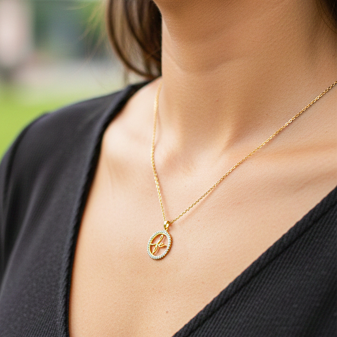 Cuello de modelo usando una cadena con un dije en forma de palabra fe en oro amarillo de 18 quilates con cristales de Joyería Caracas.
