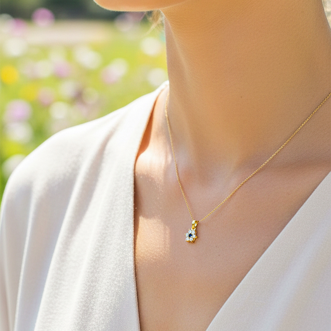 Cuello de modelo usando una cadena con un dije en forma de flor de 6 pétalos en oro amarillo de 18 quilates con cristales blancos y azul de Joyería Caracas.