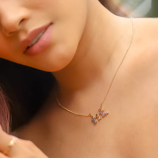 Cuello de mujer usando una gargantilla con dije de familia con un perro en oro amarillo de 18 quilates y cristales de color azul, rosa y blanco de Joyería Caracas. 