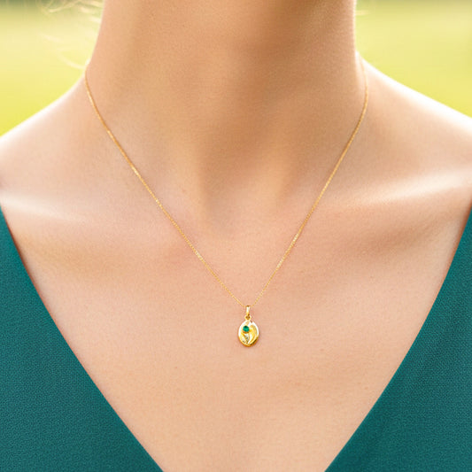 Cuello de modelo usando una cadena con un dije en forma de grano de café en oro amarillo de 18 quilates con cristal verde de Joyería Caracas.
