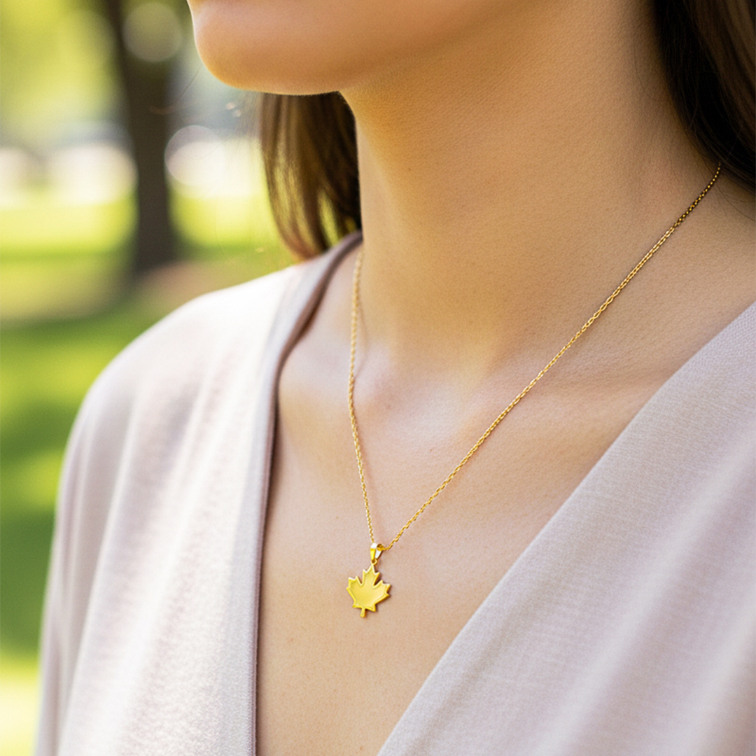 Cuello de modelo usando una cadena con un dije en forma de hoja de arce en oro amarillo de 18 quilates de Joyería Caracas.