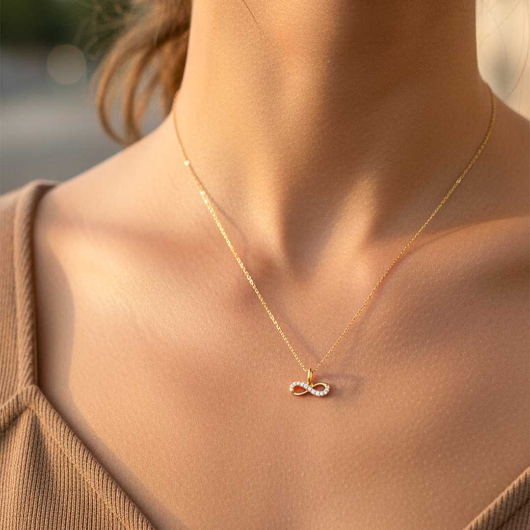 Cuello de modelo usando una cadena con un dije en forma de infinito en oro amarillo de 18 quilates con cristales de Joyería Caracas.