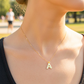 Cuello de modelo usando una cadena con un dije de letra A lisa en oro amarillo de 18 quilates de Joyería Caracas.