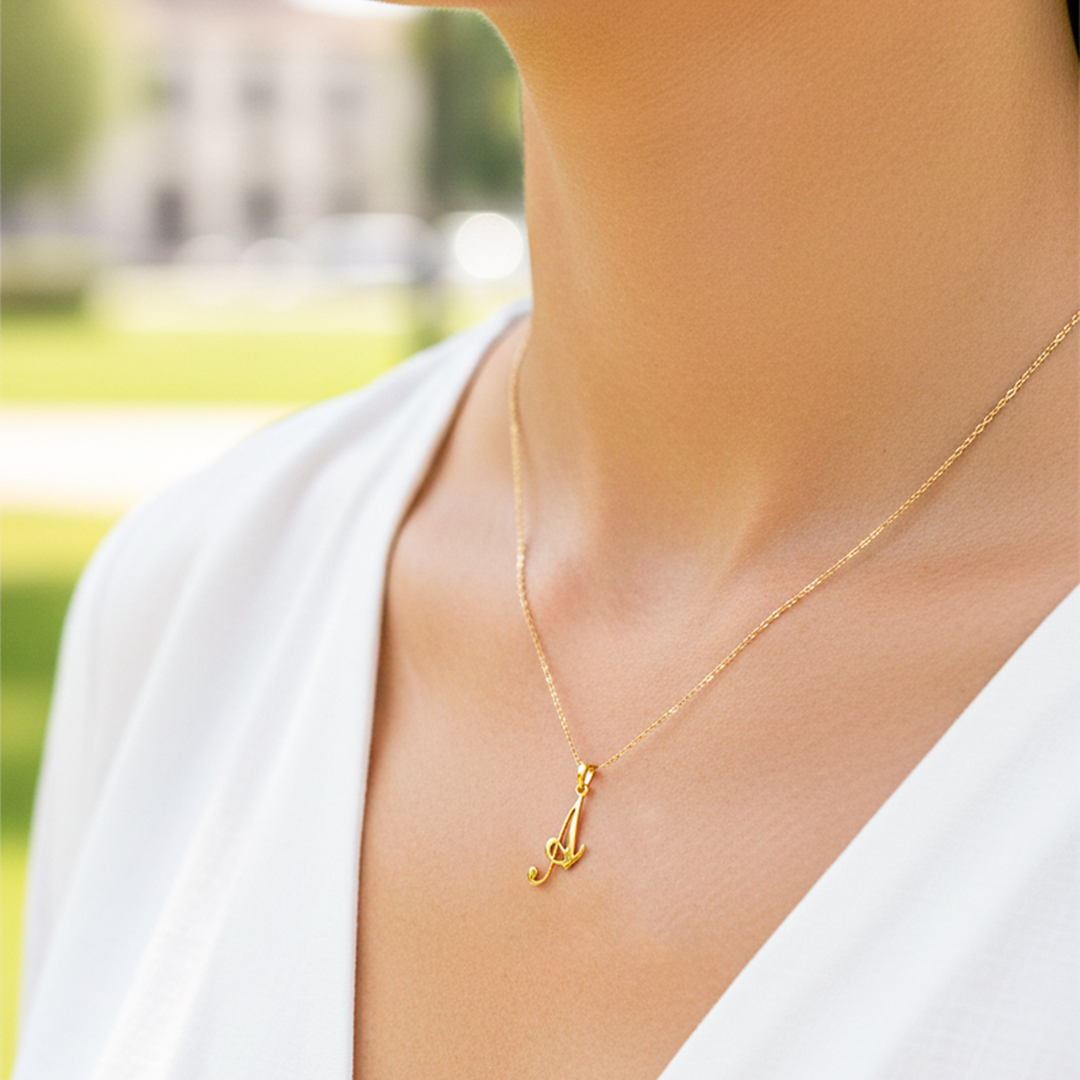Cuello de modelo usando una cadena con un dije de la letra A cursiva en oro amarillo de 18 quilates de Joyería Caracas.