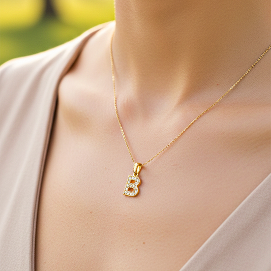 Cuello de modelo usando una cadena con un dije en forma de la letra B en oro amarillo de 18 quilates con cristales de Joyería Caracas.