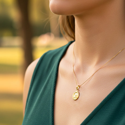 Cuello de modelo usando una cadena con un dije de la letra B con marco en oro amarillo de 18 quilates de Joyería Caracas.
