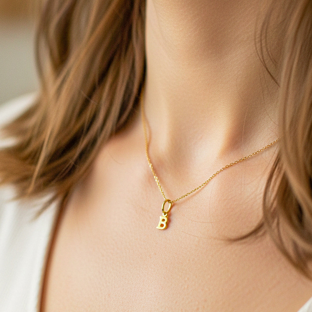 Cuello de modelo usando una cadena con un dije en forma de la letra B en oro amarillo de 18 quilates de Joyería Caracas.