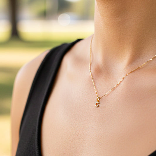 Cuello de modelo usando una cadena con un dije la letra C en oro amarillo de 18 quilates con cristales de Joyería Caracas.