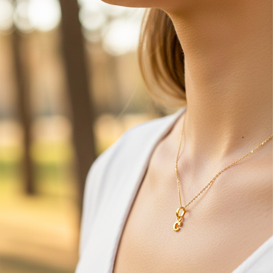 Cuello de modelo usando una cadena con un dije en forma de la letra C mini en oro amarillo de 18 quilates de Joyería Caracas.