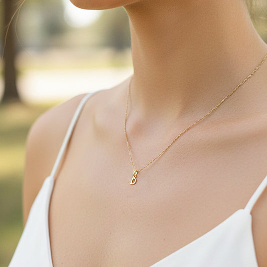 Cuello de modelo usando una cadena con un dije en forma de letra D en oro amarillo de 18 quilates de Joyería Caracas.