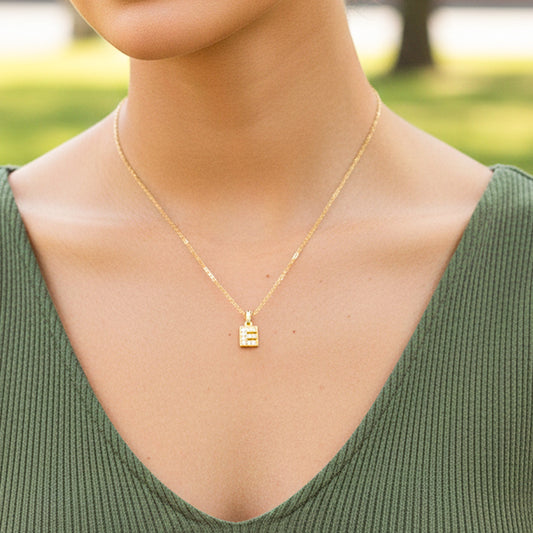 Cuello de modelo usando una cadena con un dije en forma de la letra E en oro amarillo de 18 quilates con cristales de Joyería Caracas.