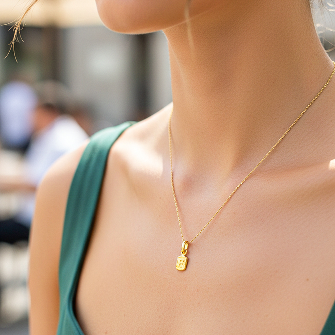 Cuello de modelo usando una cadena con un dije en forma de la letra F en oro amarillo de 18 quilates de Joyería Caracas.