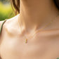 Cuello de modelo usando una cadena con un dije de la letra G en oro amarillo de 18 quilates con cristales de Joyería Caracas.