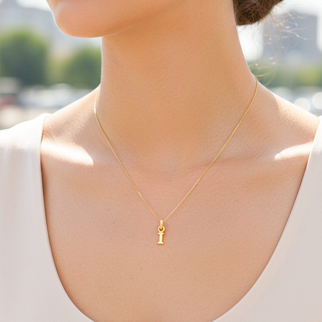 Cuello de modelo usando una cadena con un dije en forma de la letra I mini en oro amarillo de 18 quilates de Joyería Caracas.