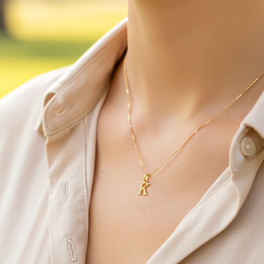 Cuello de modelo usando una cadena con un dije en forma de la letra K en oro amarillo de 18 quilates con cristales de Joyería Caracas.