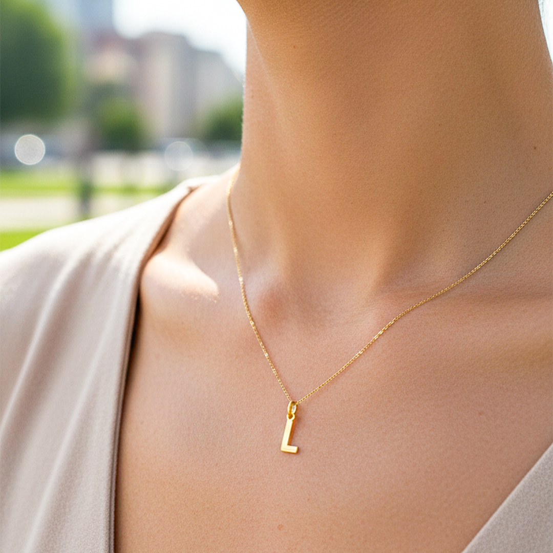 Cuello de modelo usando una cadena con un dije de letra L lisa en oro amarillo de 18 quilates de Joyería Caracas.