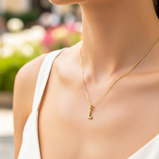 Cuello de modelo usando una cadena con un dije de la letra L en oro amarillo de 18 quilates con cristales de Joyería Caracas.