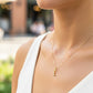 Cuello de modelo usando una cadena con un dije en forma de la letra L en oro amarillo de 18 quilates con cristales de Joyería Caracas.