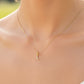 Cuello de modelo usando una cadena con un dije de la letra L en oro amarillo de 18 quilates con cristales de Joyería Caracas.