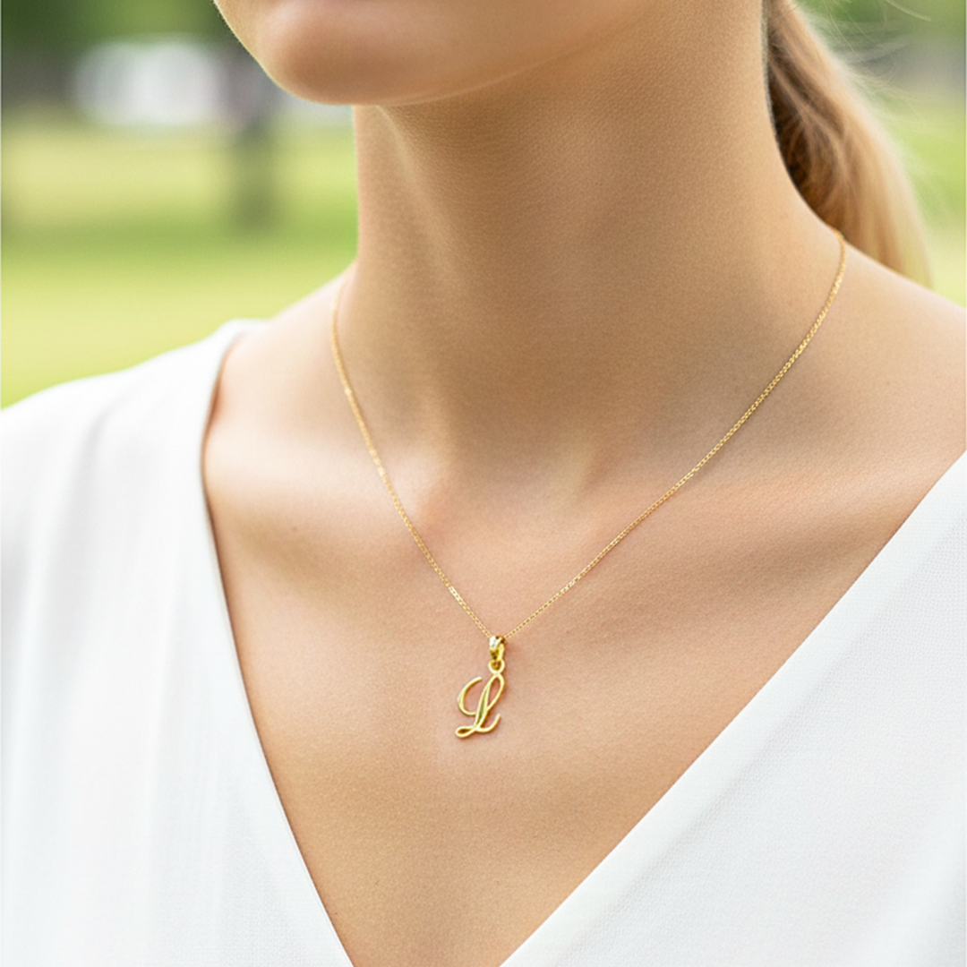 Cuello de modelo usando una cadena con un dije de la letra L cursiva en oro amarillo de 18 quilates de Joyería Caracas.