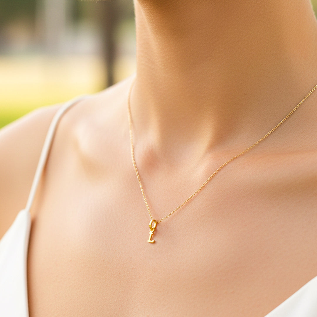 Cuello de modelo usando una cadena con un dije en forma de letra L en oro amarillo de 18 quilates de Joyería Caracas.