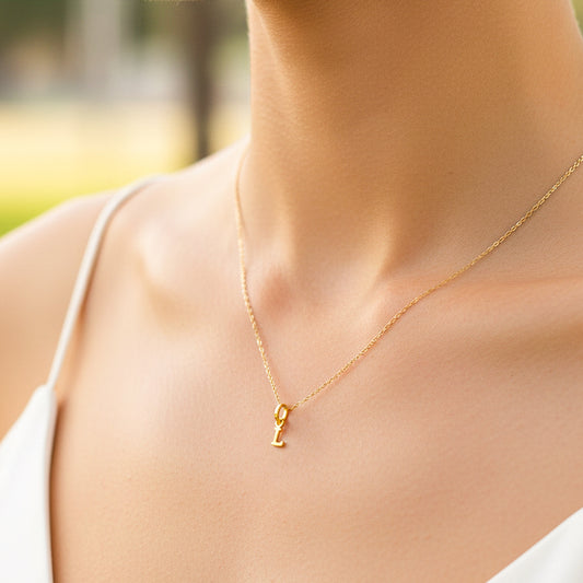 Cuello de modelo usando una cadena con un dije en forma de letra L en oro amarillo de 18 quilates de Joyería Caracas.