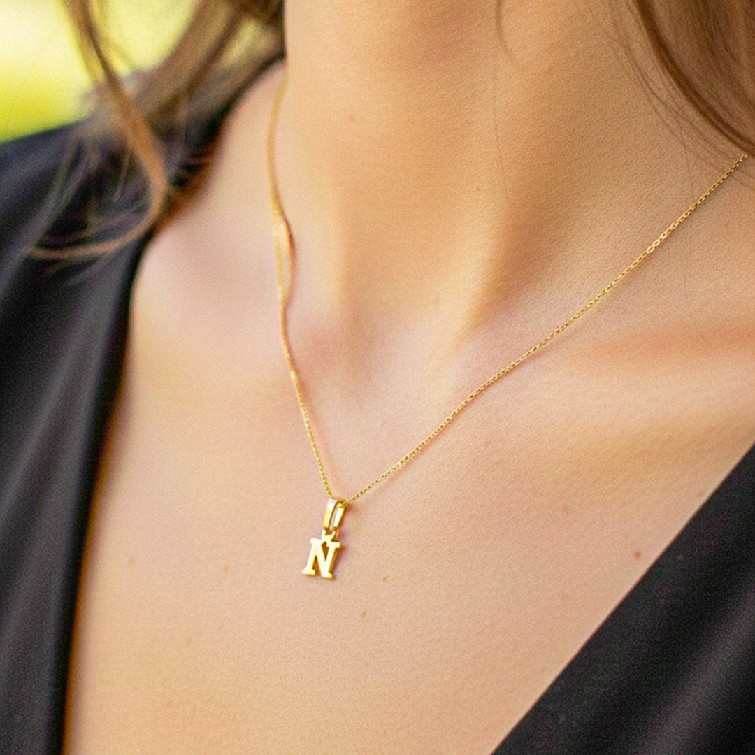 Cuello de modelo usando una cadena con un dije en forma de la letra N en oro amarillo de 18 quilates de Joyería Caracas.
