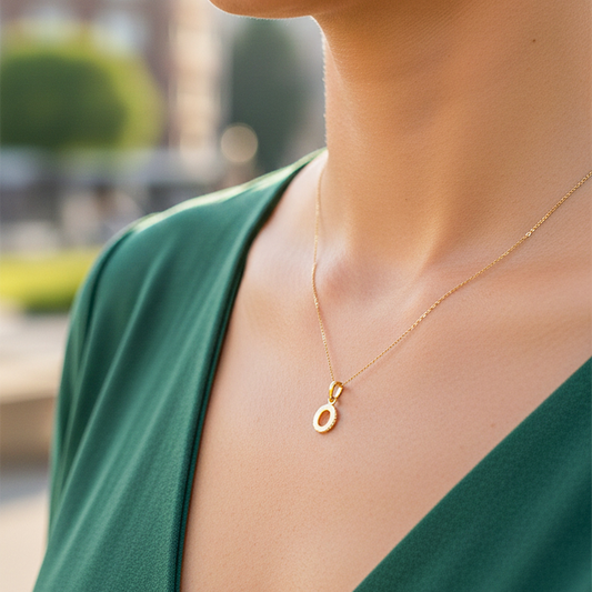 Cuello de modelo usando una cadena con un dije en forma de la letra O en oro amarillo de 18 quilates de Joyería Caracas.