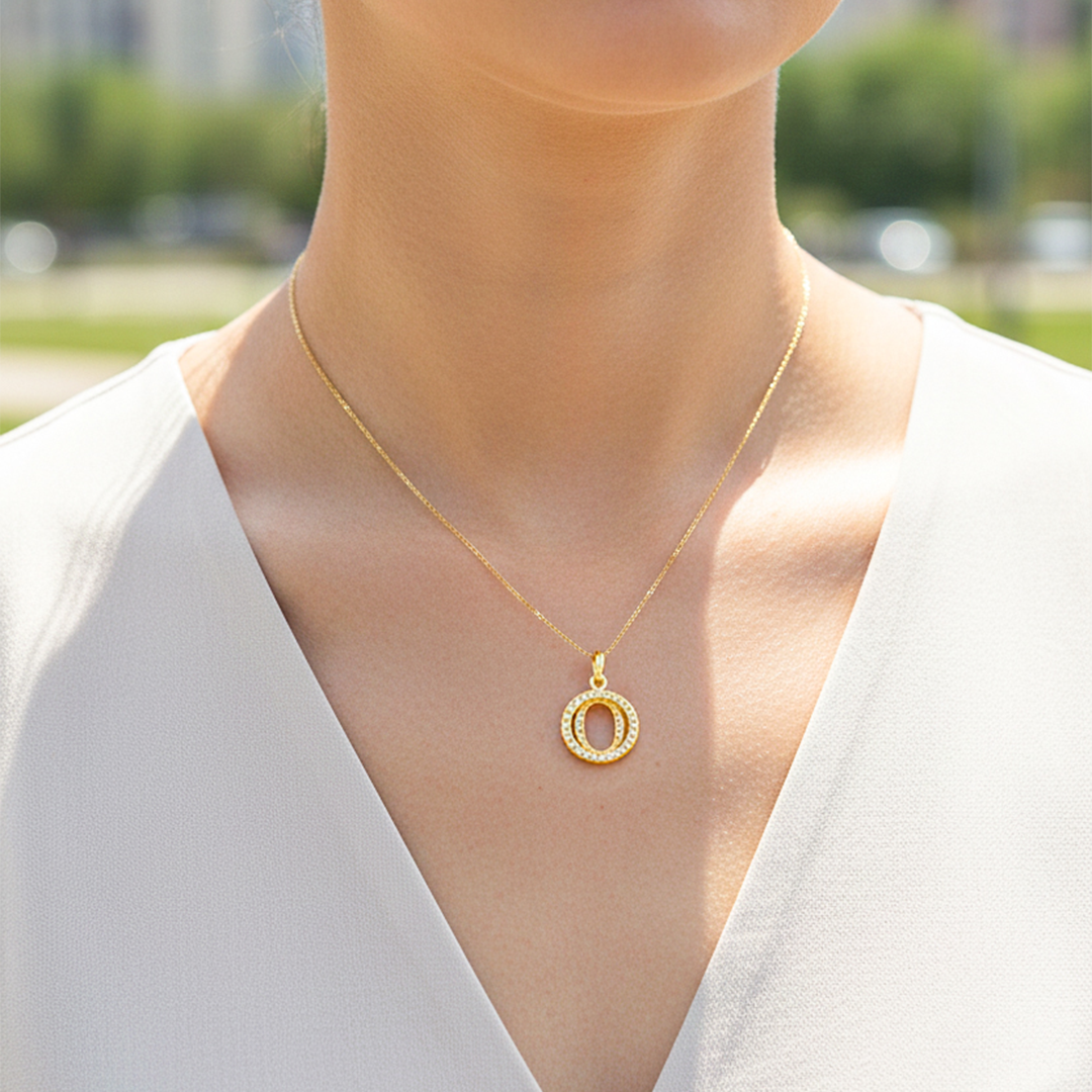 Cuello de modelo usando una cadena con un dije de la letra O en oro amarillo de 18 quilates con cristales de Joyería Caracas. 