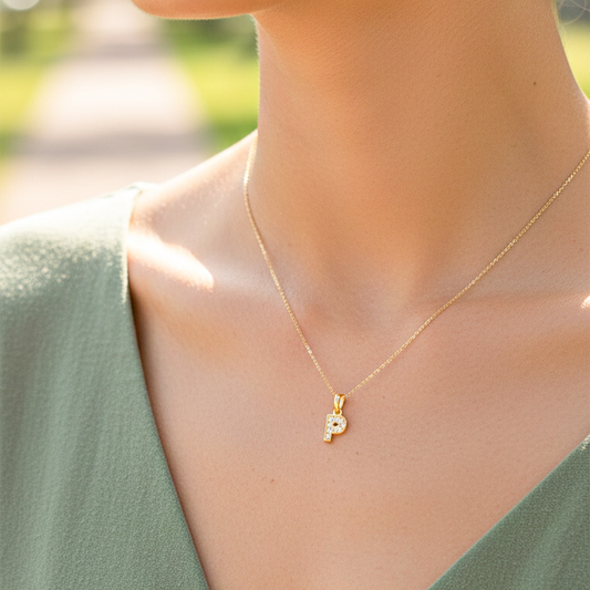 Cuello de modelo usando una cadena con un dije en forma de letra P en oro amarillo mini de 18 quilates con cristales de Joyería Caracas.