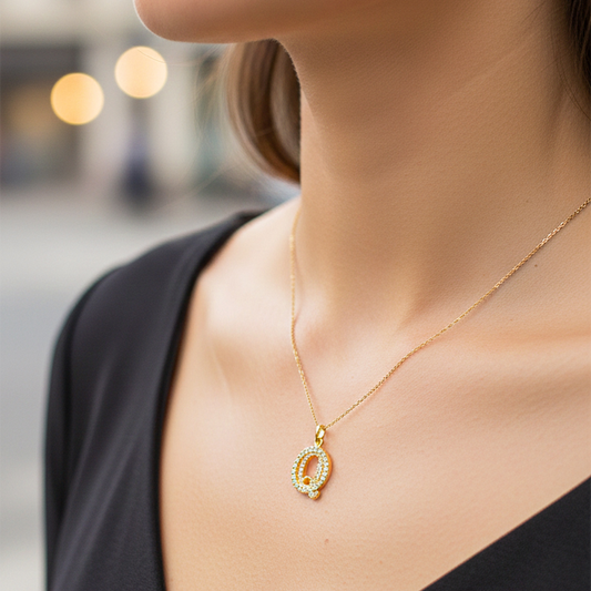 Cuello de modelo usando una cadena con un dije de la letra Q en oro amarillo de 18 quilates con cristales de Joyería Caracas.