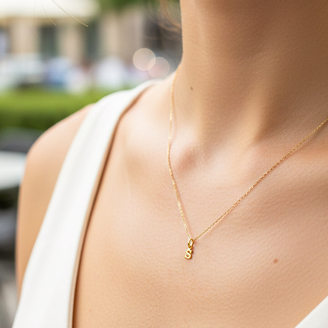 Cuello de modelo usando una cadena con un dije en forma de letra S en oro amarillo de 18 quilates de Joyería Caracas.