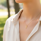 Cuello de modelo usando una cadena con un dije en forma de la letra T en oro amarillo de 18 quilates de Joyería Caracas.