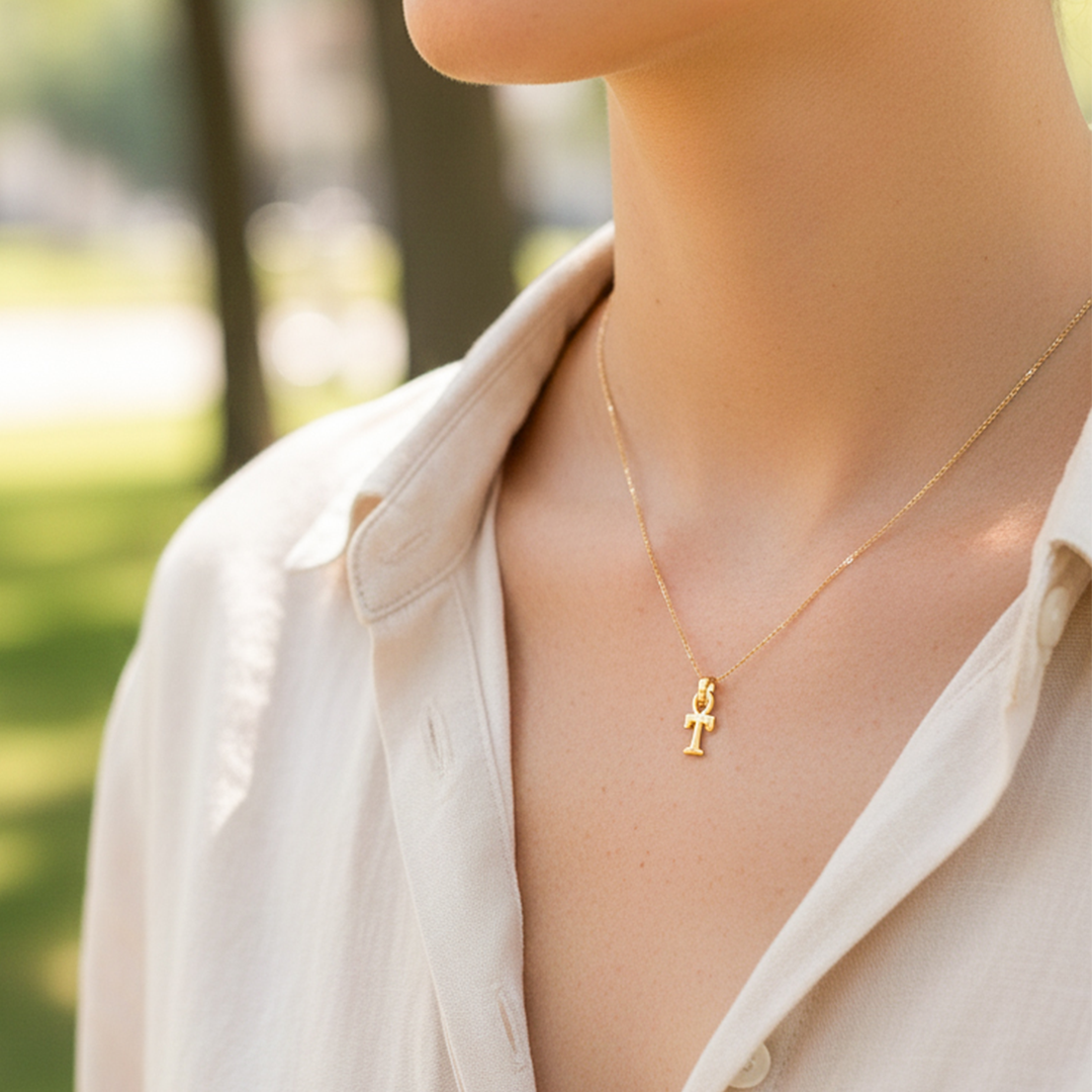Cuello de modelo usando una cadena con un dije en forma de la letra T en oro amarillo de 18 quilates de Joyería Caracas.