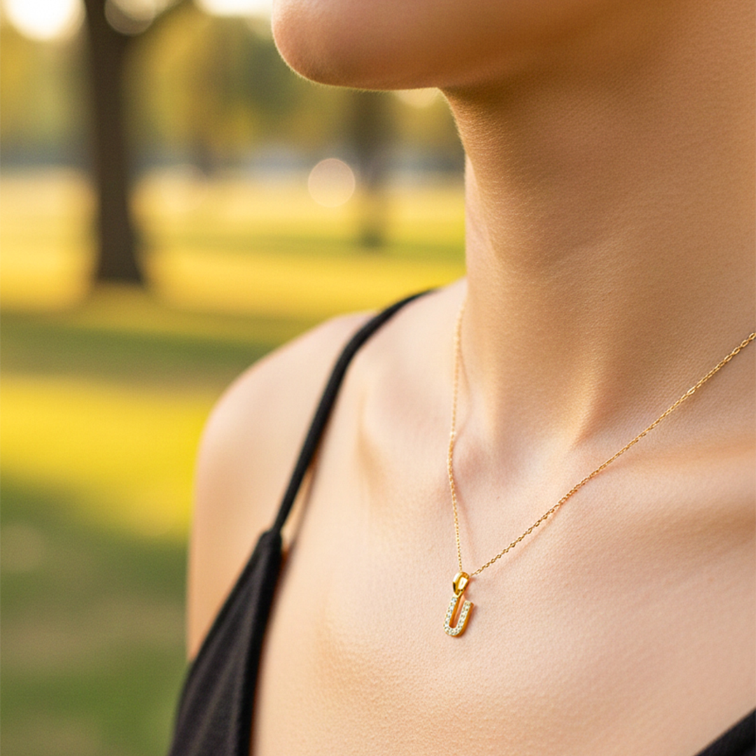 Cuello de modelo usando una cadena con un dije en forma de la letra U en oro amarillo de 18 quilates con cristales de Joyería Caracas.