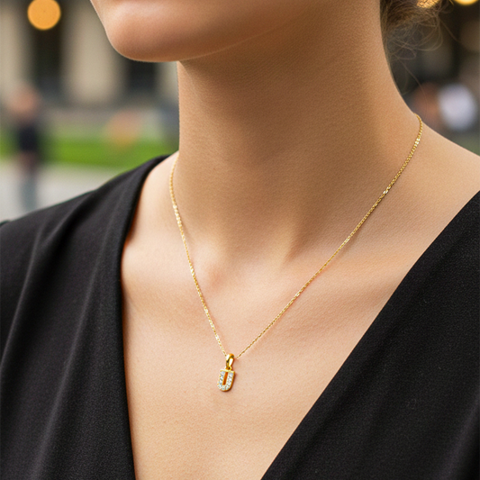 Cuello de modelo usando una cadena con un dije en forma de la letra U en oro amarillo de 18 quilates con cristales de Joyería Caracas.