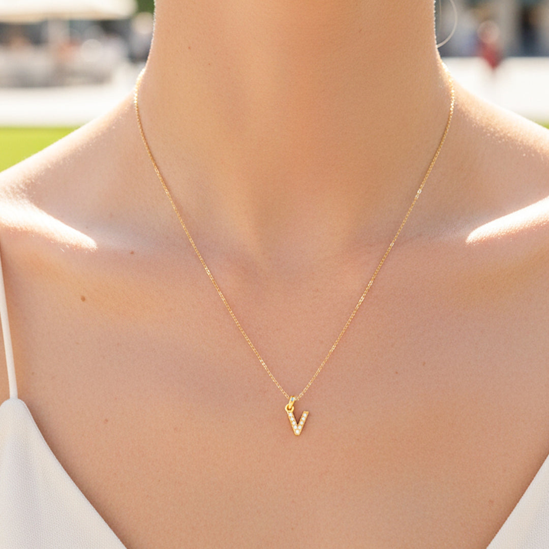 Cuello de modelo usando una cadena con un dije en forma de letra V en oro amarillo de 18 quilates con cristales de Joyería Caracas.