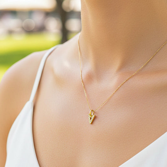 Cuello de modelo usando una cadena con un dije de la letra V en oro amarillo de 18 quilates con cristales de Joyería Caracas.