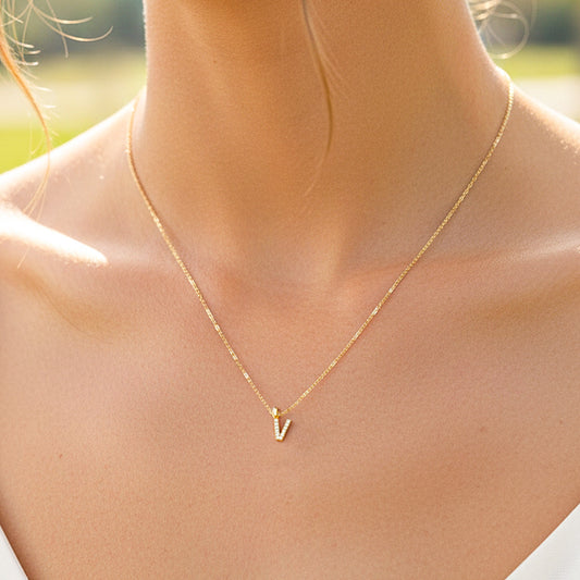 Cuello de modelo usando una cadena con un dije en forma de la letra V en oro amarillo de 18 quilates con cristales de Joyería Caracas.