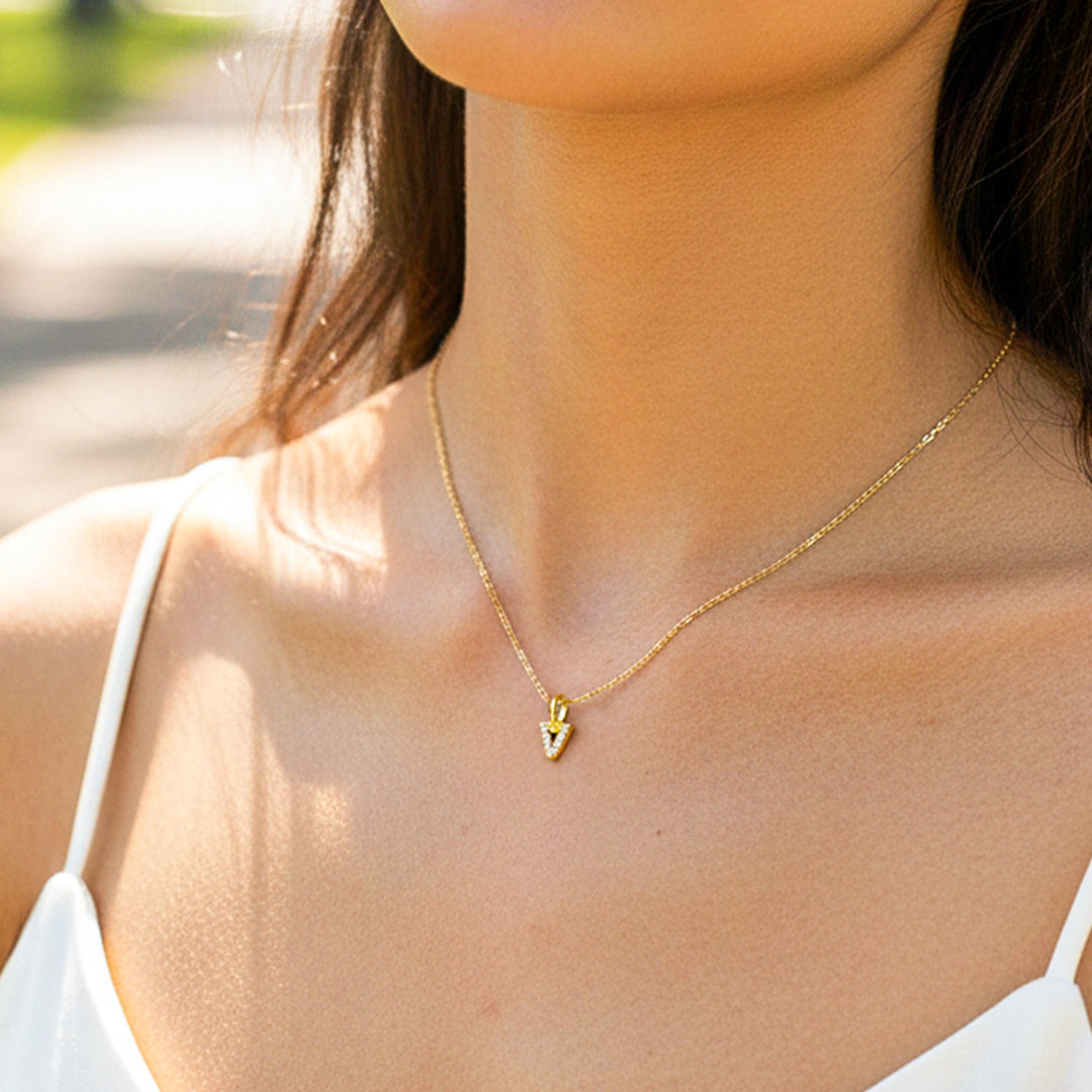 Cuello de modelo usando una cadena con un dije de la letra V en oro amarillo de 18 quilates con cristales de Joyería Caracas.