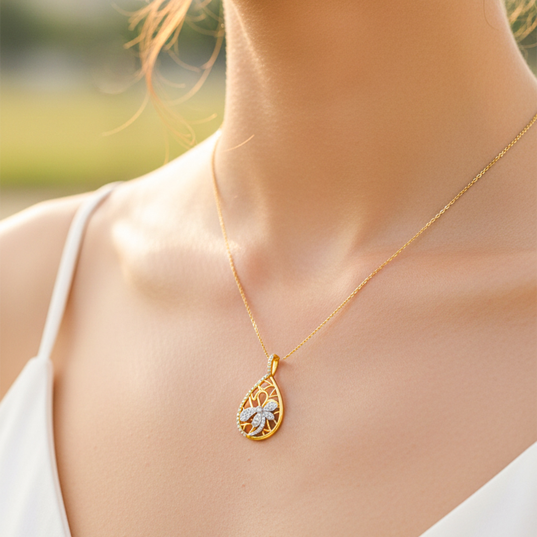 Cuello de modelo usando una cadena con un dije en forma de gota con libélula en oro amarillo y blanco de 18 quilates y con cristales de Joyería Caracas.