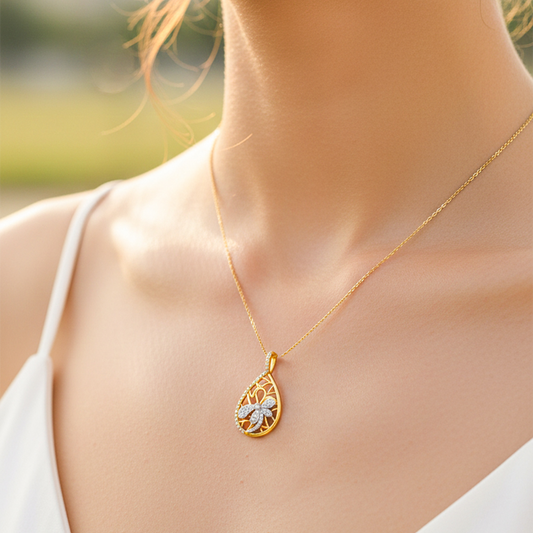 Cuello de modelo usando una cadena con un dije en forma de gota con libélula en oro amarillo y blanco de 18 quilates y con cristales de Joyería Caracas.
