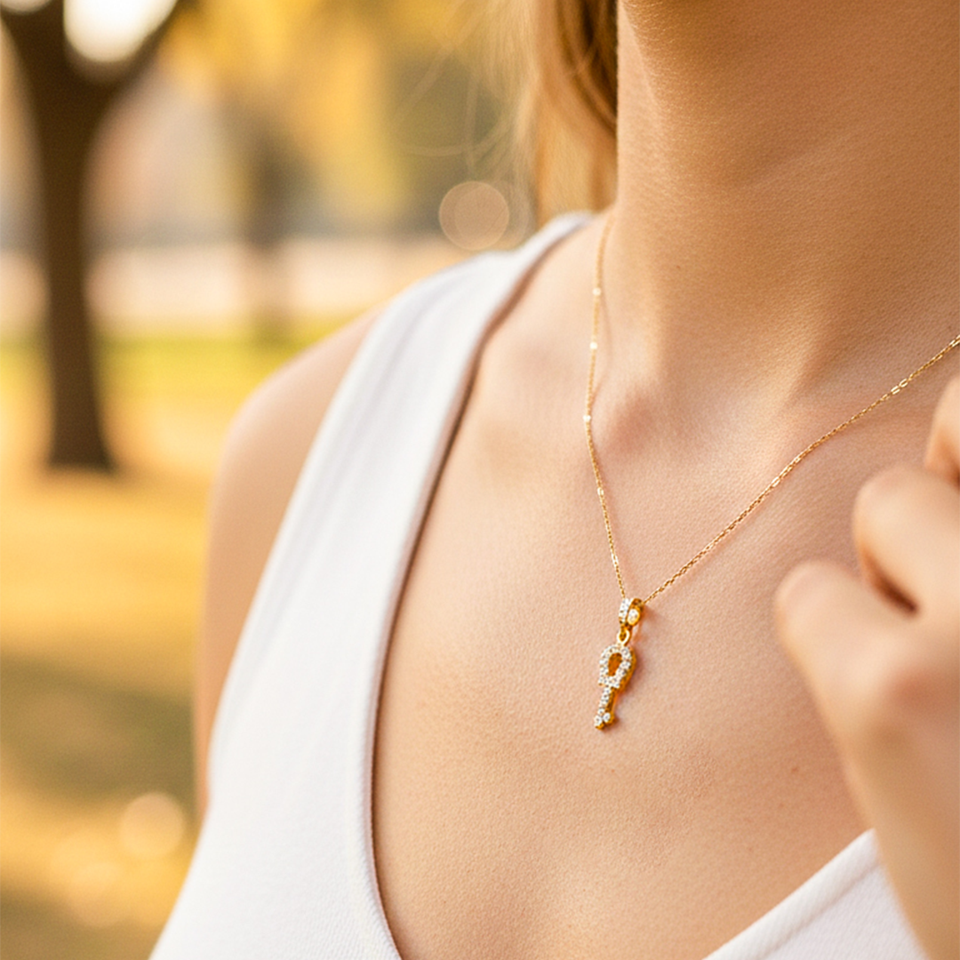 Cuello de modelo usando una cadena con un dije en forma de llave en oro amarillo de 18 quilates con cristales de Joyería Caracas.